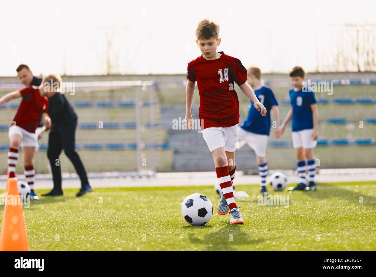 Action d'entraînement des équipes de football des garçons, âgés de 10 à 12 ans, jouant sur le terrain d'entraînement de football. L'équipe de football de l'école lors d'une séance d'entraînement avec un entraîneur Banque D'Images