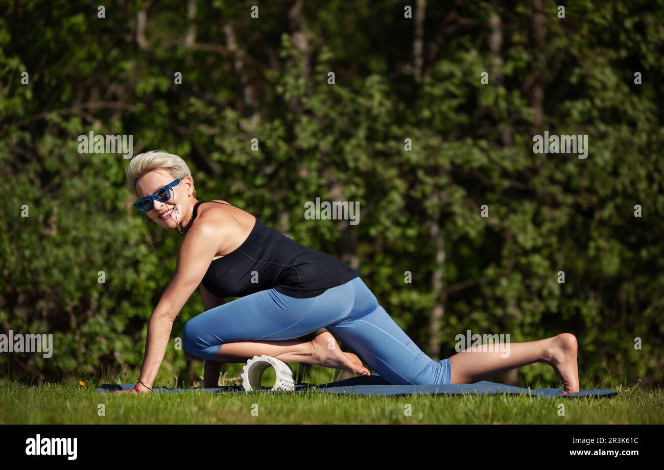 Joyeuse femme d'âge moyen faisant de l'exercice physique à la nature verte, à l'extérieur. Modèle femelle mature engagé dans l'activité physique et a bien formé b Banque D'Images