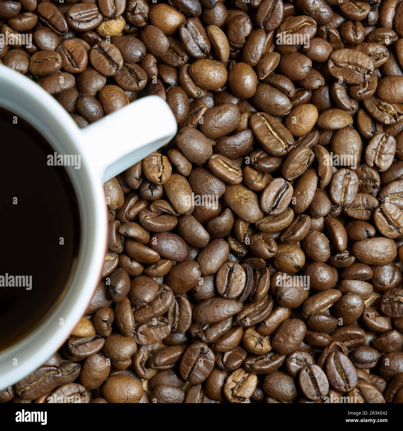 Grains de café rôtis et une tasse de café sur une table Banque D'Images