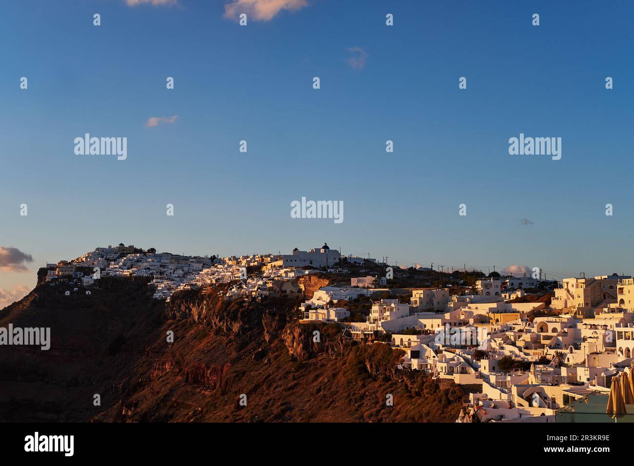 Vue panoramique aérienne du village d'Imerovigli et du rocher de Skaros sur l'île de Santorini, Grèce au coucher du soleil - Maisons blanches traditionnelles dans Banque D'Images