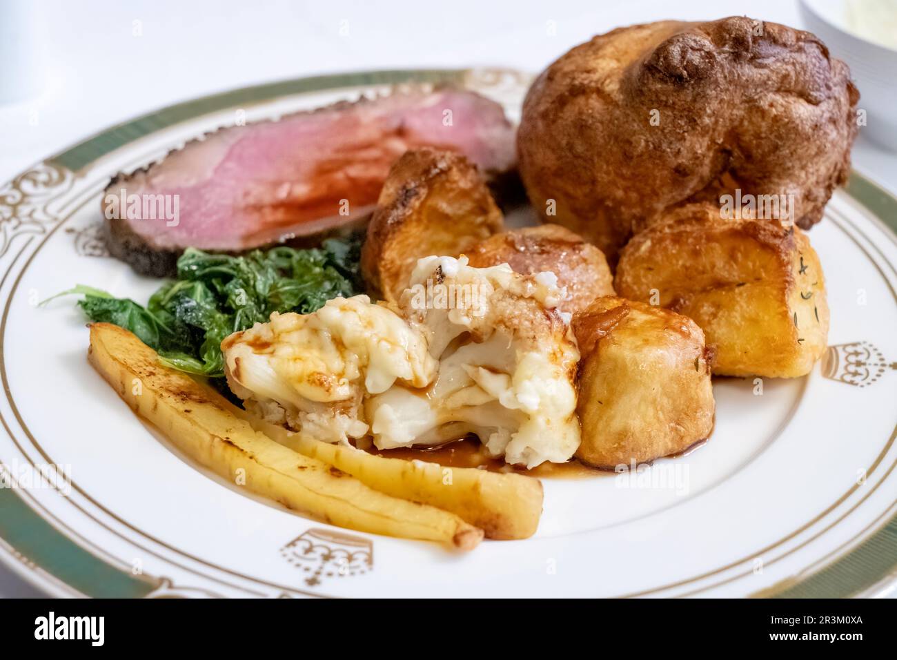 Un dîner traditionnel anglais rôti complet. Servi avec des stripine de bœuf, des pommes de terre rôties, du chou-fleur, des panais, du chou, Yorkshire pudding et sauce Banque D'Images