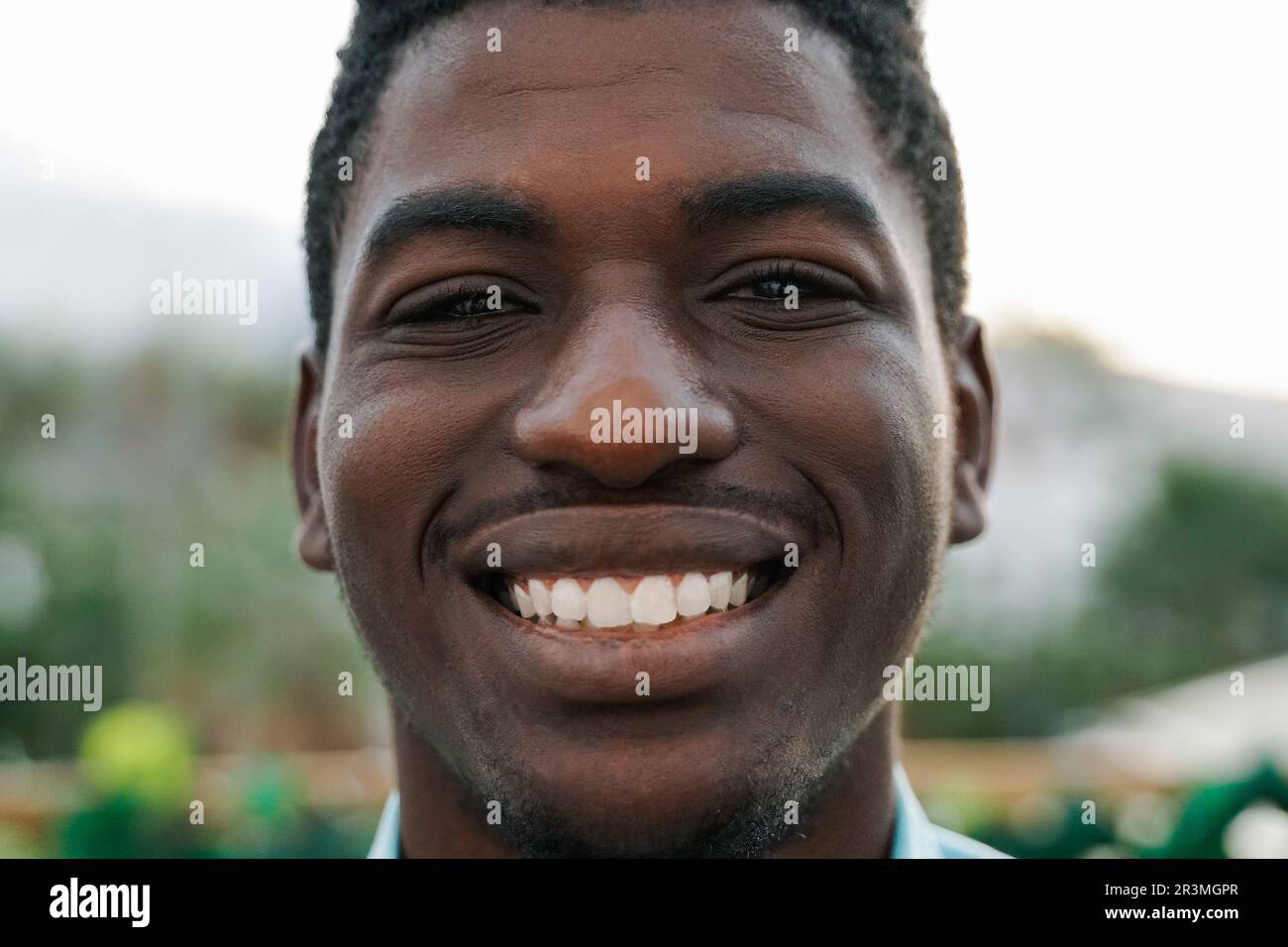 Jeune homme africain souriant à l'appareil photo avec Park City en arrière-plan Banque D'Images