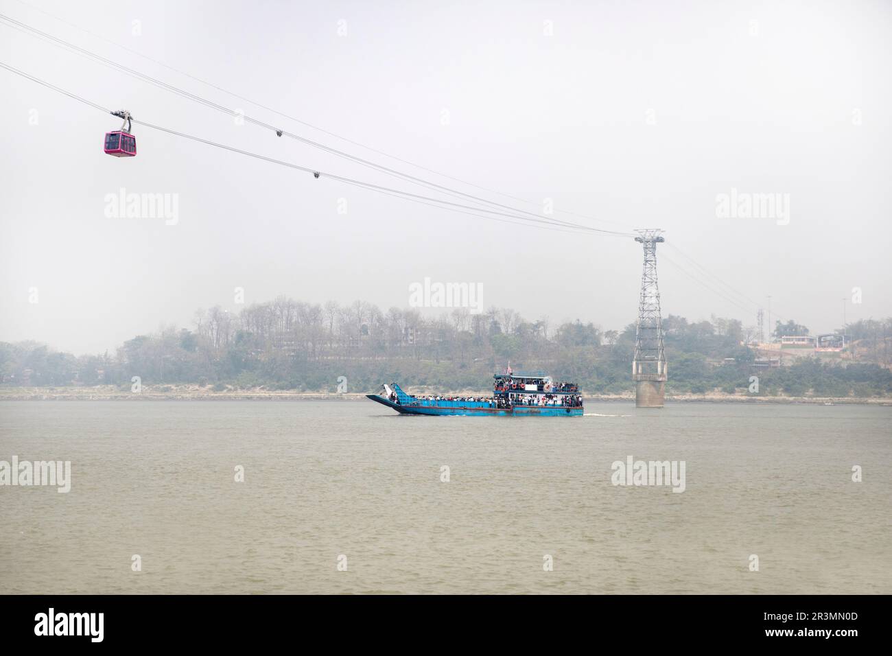Bateau à passagers traditionnel en bois sur la rivière Brahmapoutre près de Guwahati avec un téléphérique au-dessus, reliant Guwahati à l'autre rive du fleuve, Assam, Inde Banque D'Images