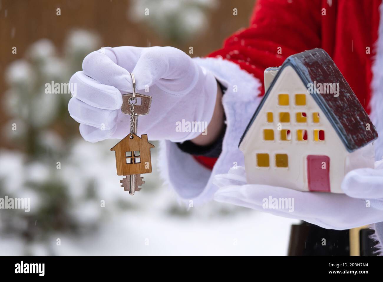 Maison clé avec porte-clés cottage dans les mains du Père Noël extérieur dans la neige. Affaire pour l'immobilier, l'achat, la construction, relocatio Banque D'Images