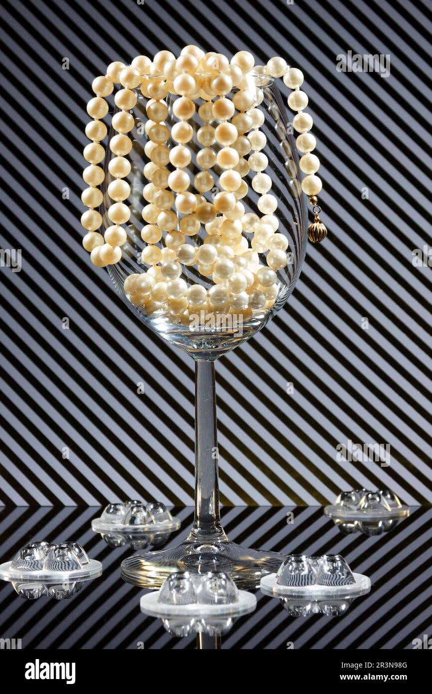 gros plan d'un verre de vin rempli de perles et d'arrière-plan avec des rayures et de vraies ombres Banque D'Images