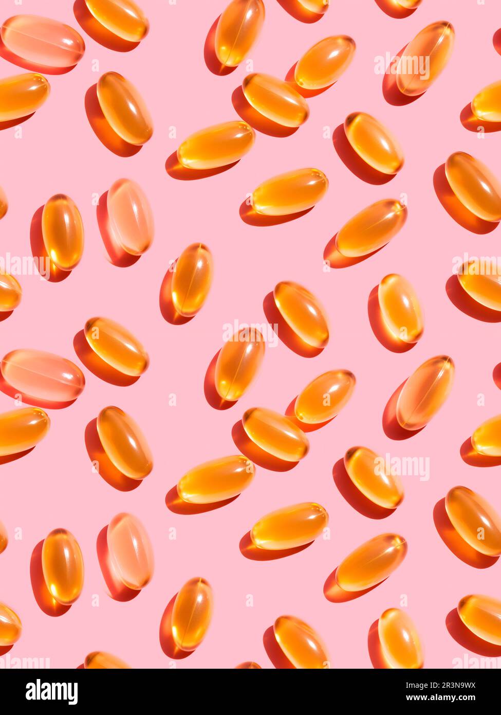 Vue de dessus composition de pilules de vitamine orange éparpillées sur fond rose dans le studio léger Banque D'Images