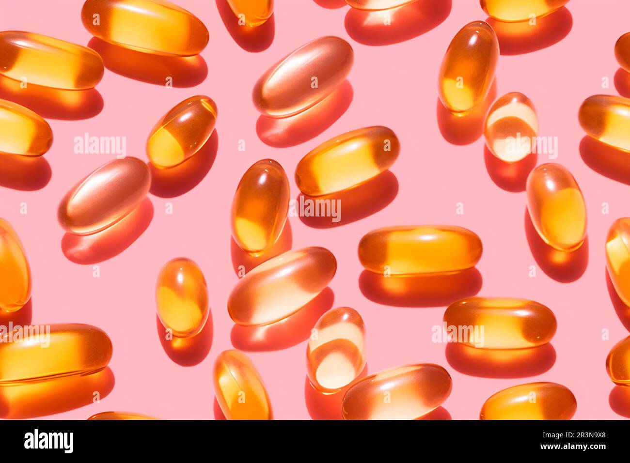 Composition de pilules de vitamine orange dispersées sur fond rose en studio léger Banque D'Images