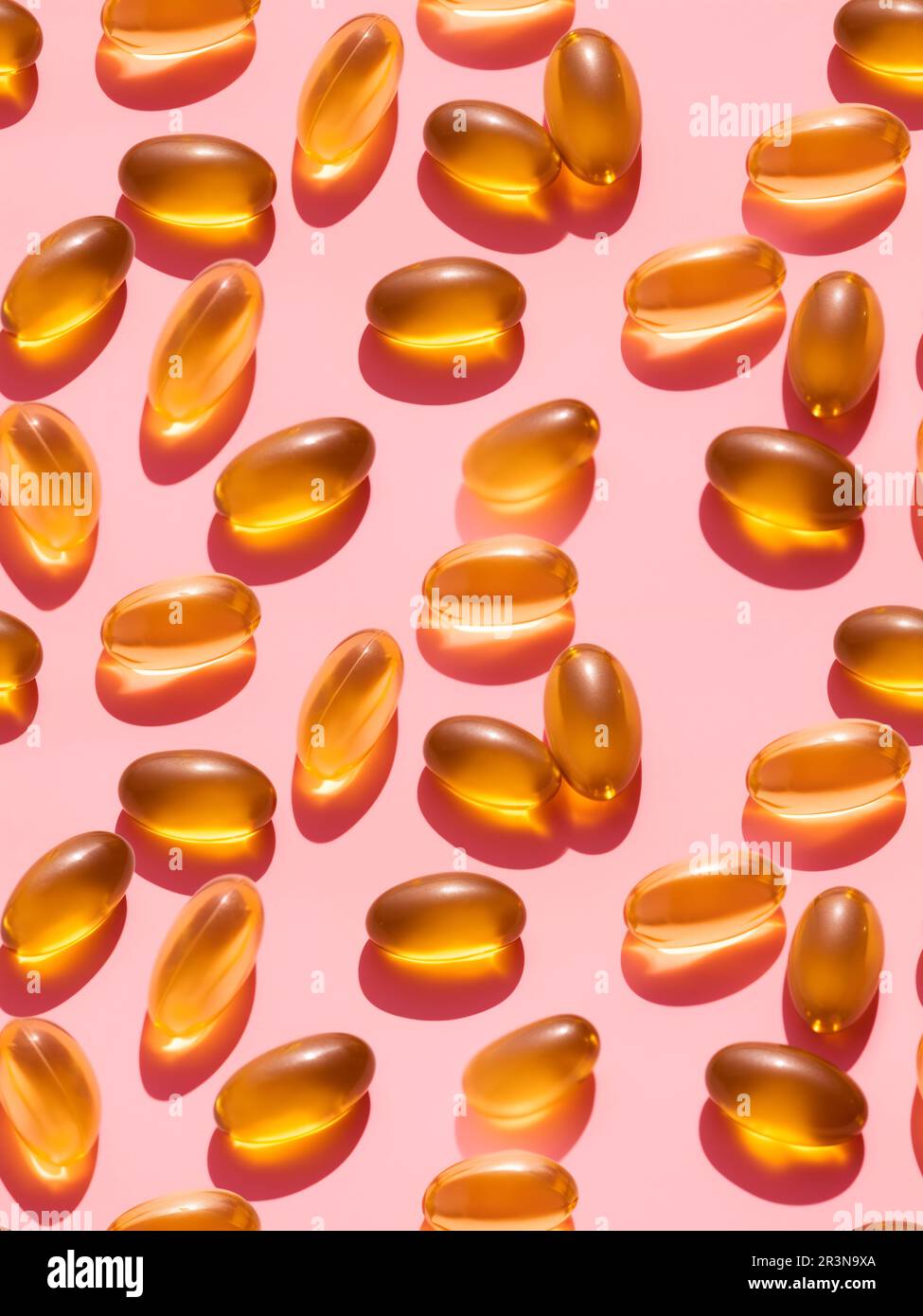 Vue de dessus composition de pilules de vitamine orange éparpillées sur fond rose dans le studio léger Banque D'Images