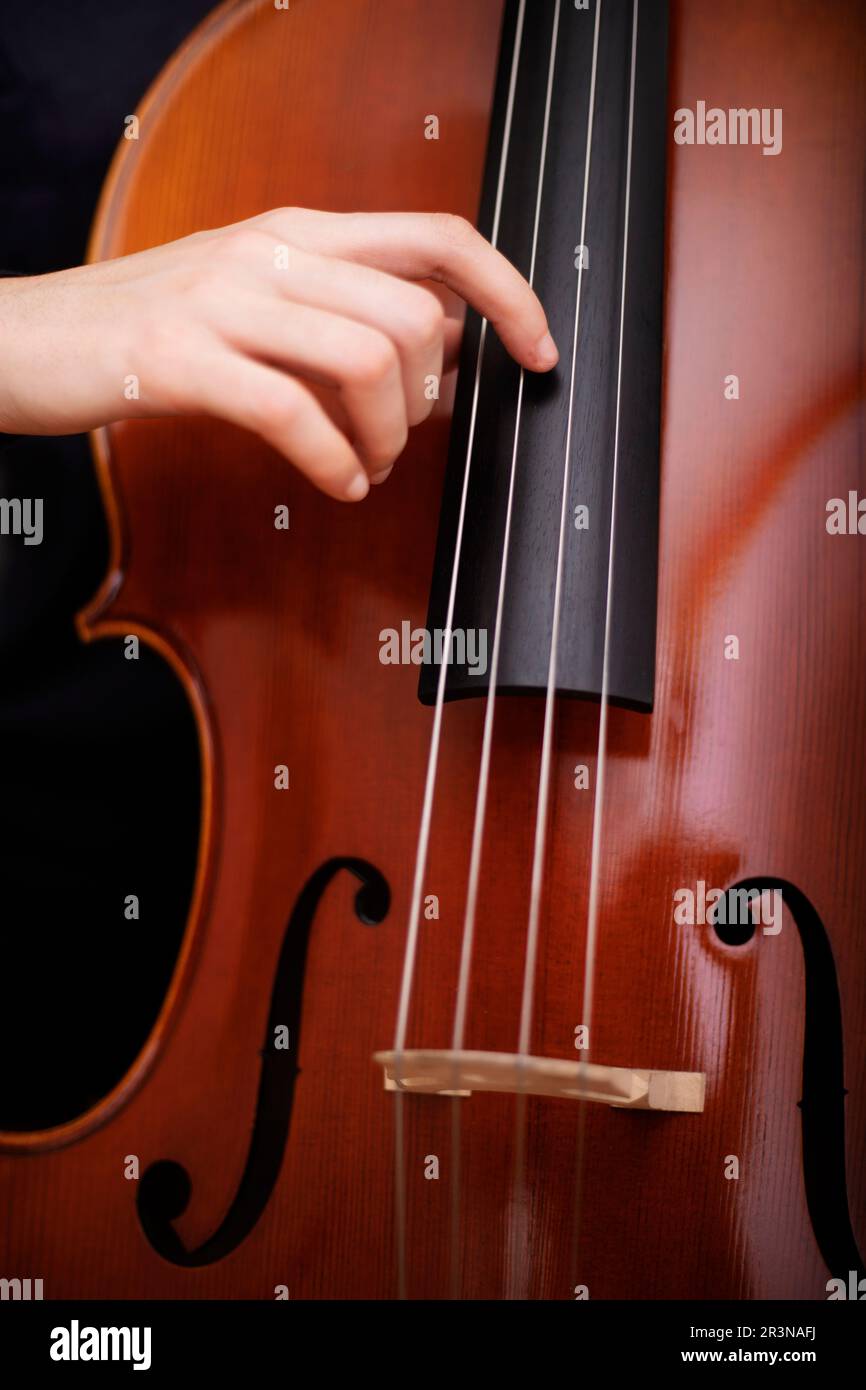 Gros plan avec crop anonyme musicienne pratiquant la musique sur violoncelle  acoustique en tirant les cordes avec la main Photo Stock - Alamy