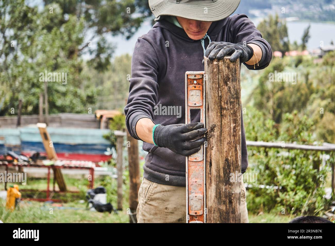 Jeune maître masculin concentré en vêtements décontractés chapeau Panama et  gants mesurant la planche en bois tout en travaillant dans la ferme dans la  communauté d'Otavalo en Equateur Photo Stock - Alamy