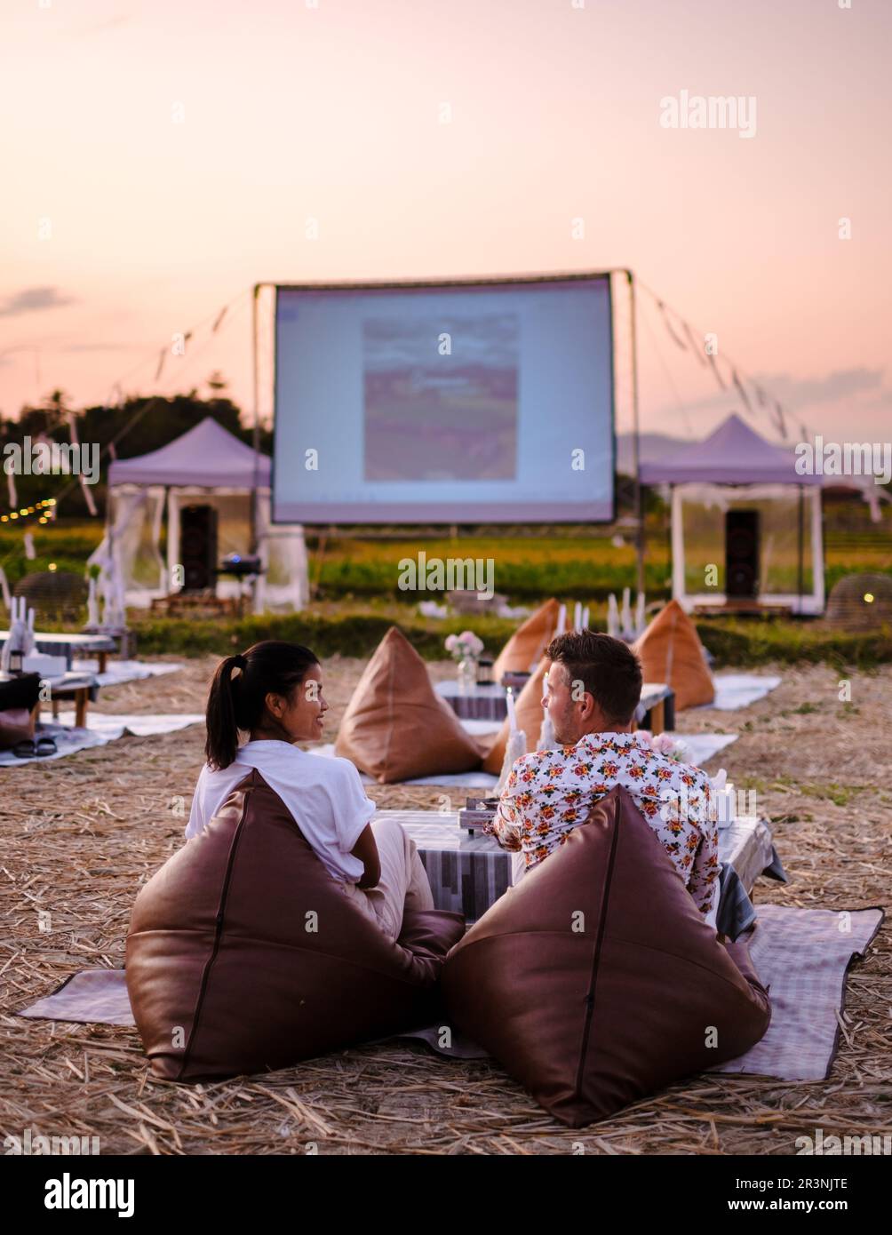 Quelques hommes et femmes regardent un film dans un cinéma en plein air dans la province de Nan, dans le nord de la Thaïlande Banque D'Images