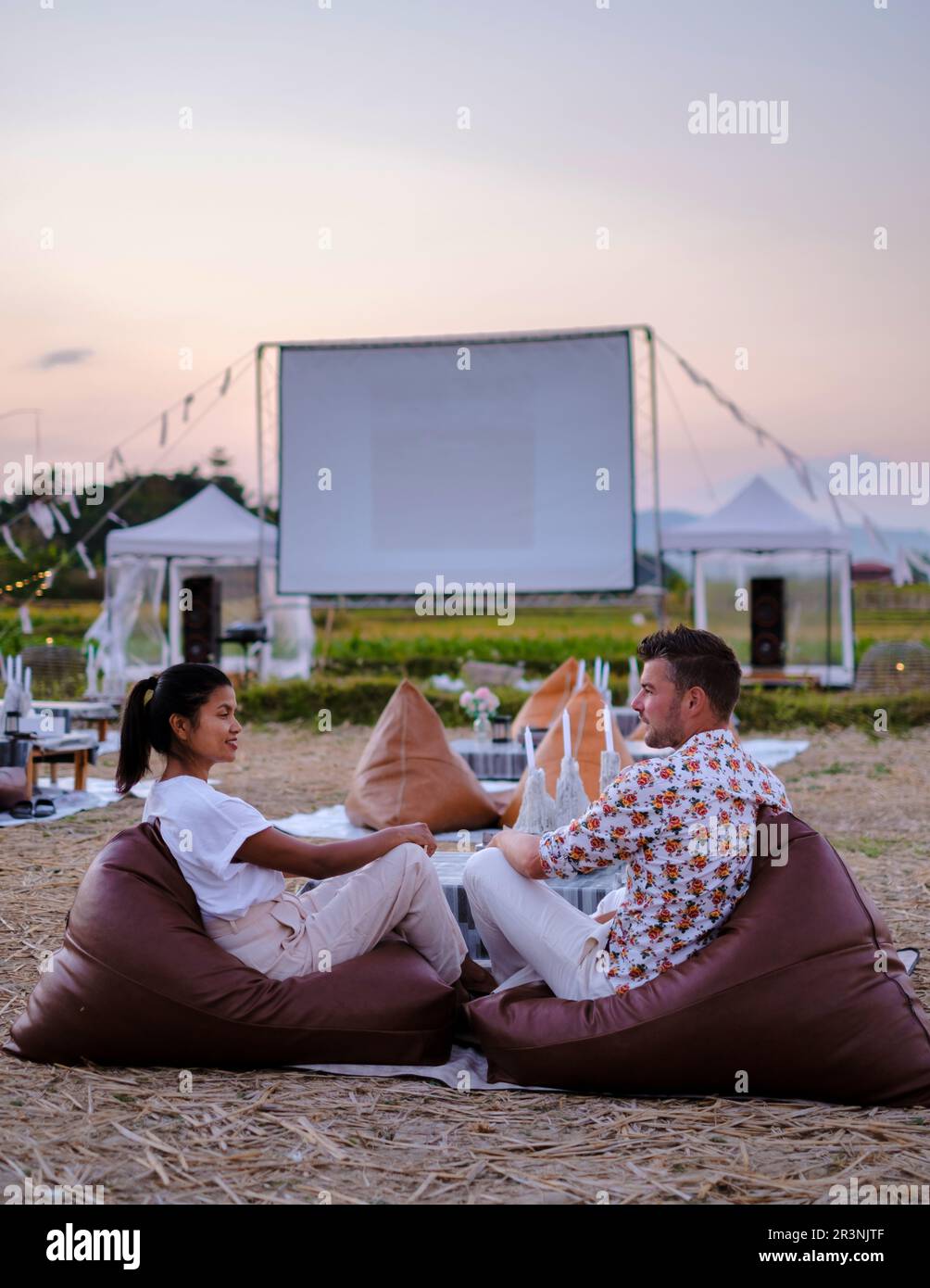 Quelques hommes et femmes regardent un film dans un cinéma en plein air dans la province de Nan, dans le nord de la Thaïlande Banque D'Images