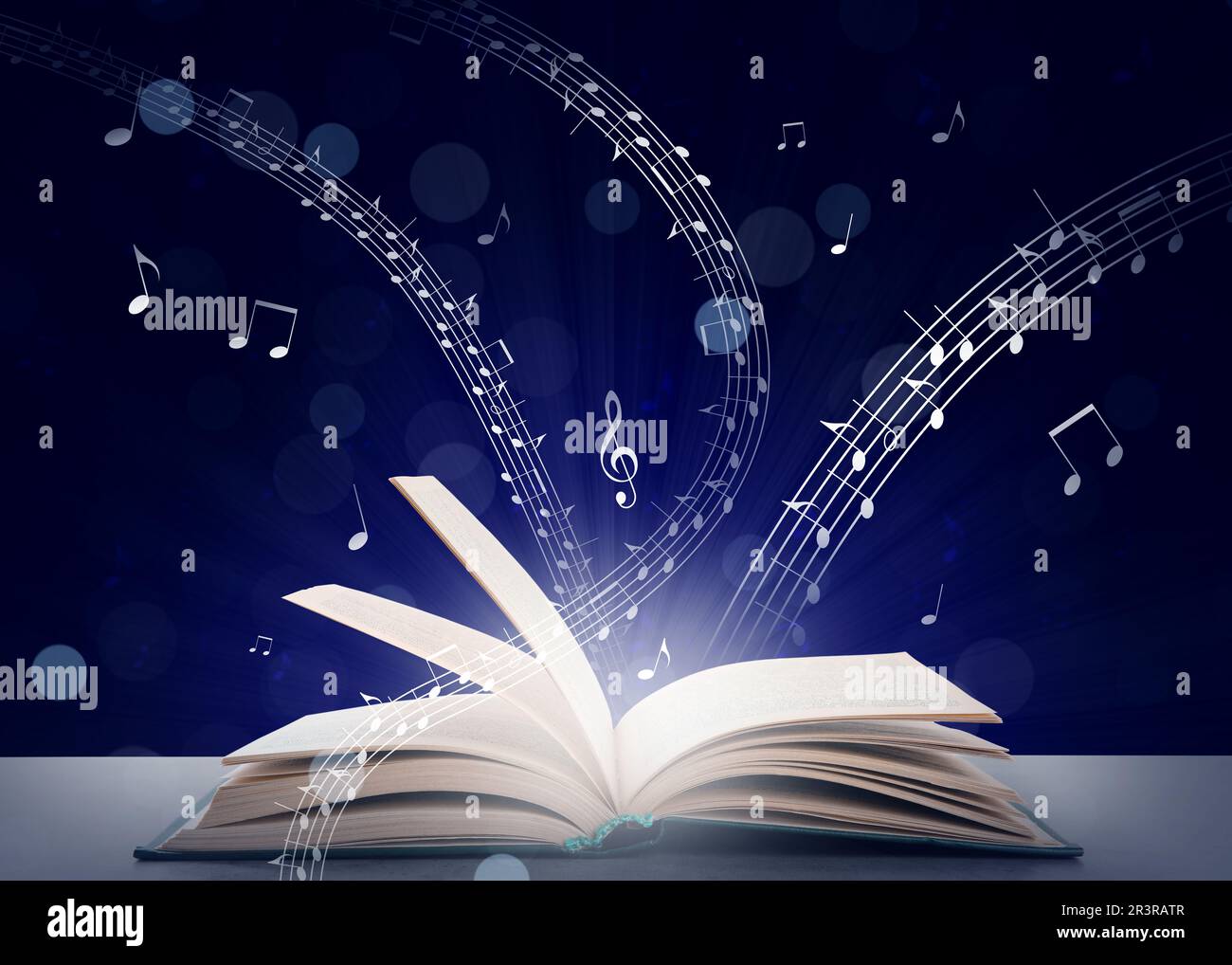 Musique provenant du livre. Symboles musicaux survolant le dôme sur une table grise sur fond bleu foncé Banque D'Images