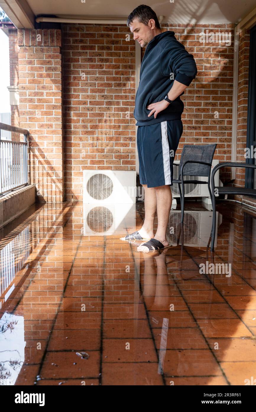 Un homme nettoyant balcon inondé après une forte pluie Banque D'Images