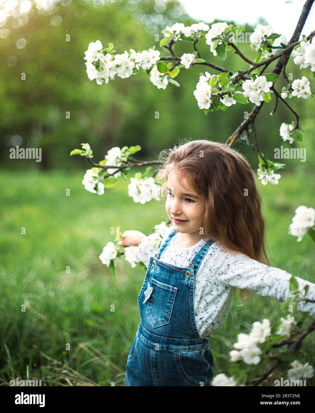 Une jolie petite fille de 5 ans dans un verger de pomme blanc en fleurs au printemps. Printemps, verger, floraison, allergie, printemps f Banque D'Images