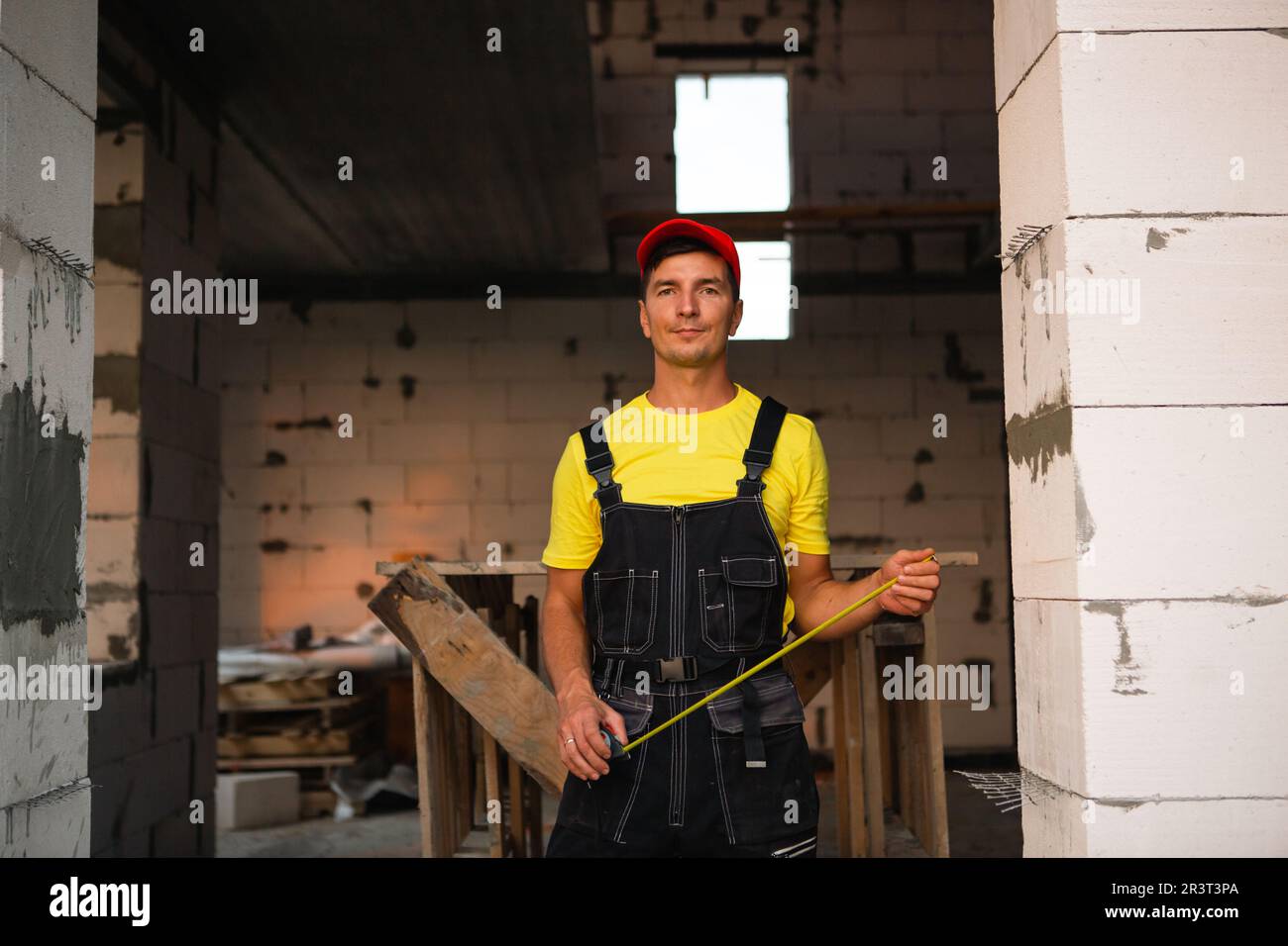 L'ingénieur du chantier de construction mesure la longueur de l'ouverture de la fenêtre et du mur de briques à l'aide d'un mètre ruban. Homme dans Banque D'Images