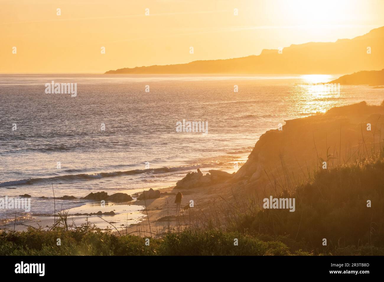 Les gens marchent le long de la plage au coucher du soleil à Playa de los lances sur le détroit de Gibraltar, Tarifa, Espagne Banque D'Images