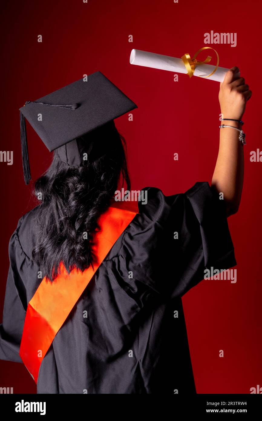 Une étudiante dans une photo de remise des diplômes. Diplôme de fin d'études avec diplôme d'études supérieures. Université, tunique avec chapeau sur le dos avec le diplôme Banque D'Images
