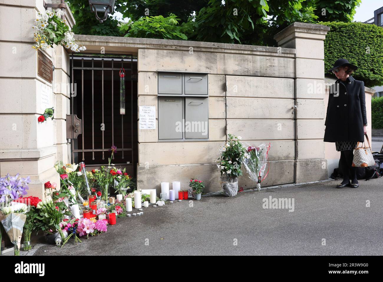 A woman stands in front of flowers and candles placed at the gate of the house of late singer and stage performer Tina Turner in Kuesnacht, Switzerland, on Thursday, May 25, 2023. Turner, the unstoppable singer and stage performer, died Wednesday, after a long illness at her home in Kuesnacht near Zurich, Switzerland, according to her manager. She was 83. (AP Photo/Arnd Wiegmann) Banque D'Images