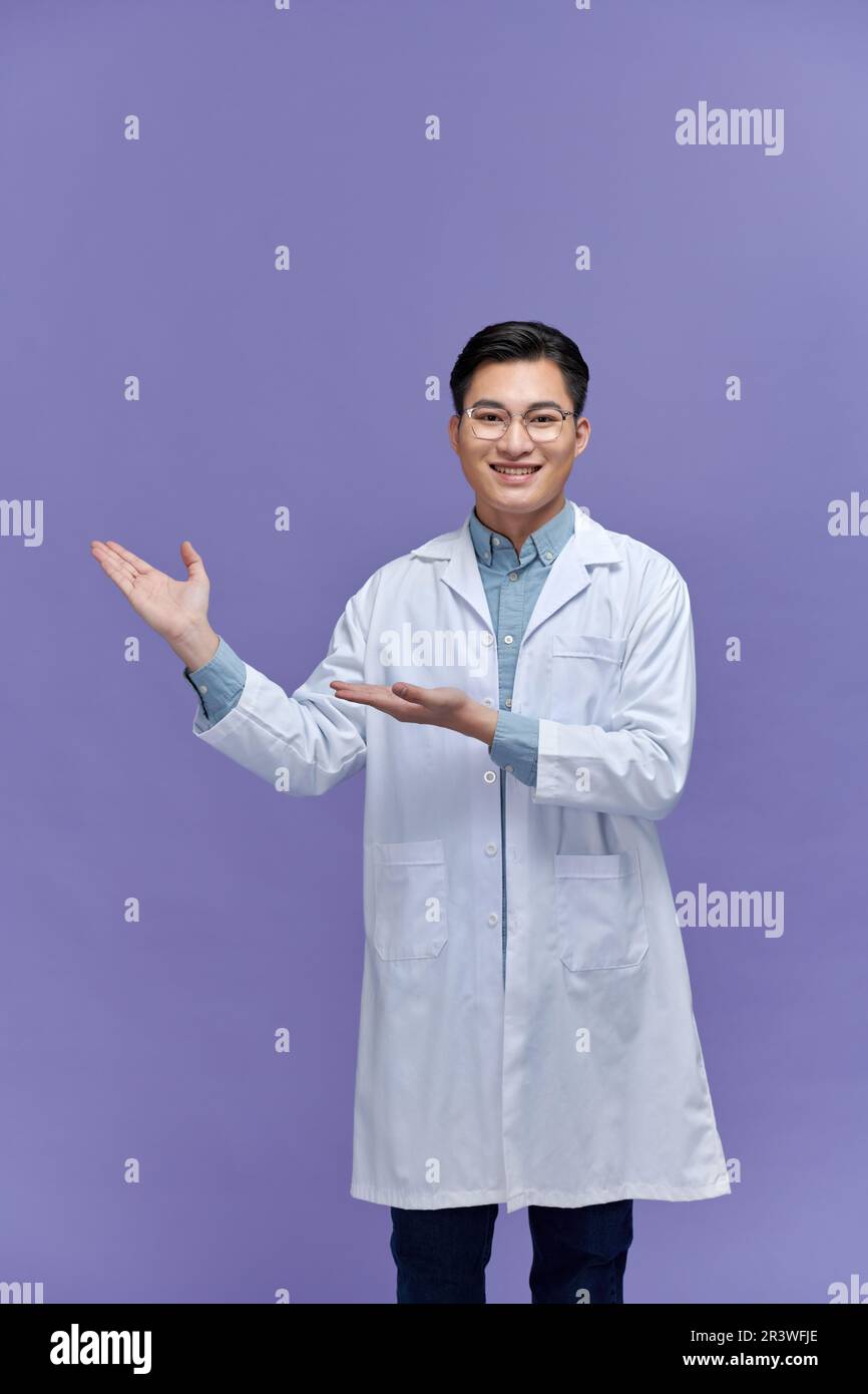 jeune homme souriant médecin montrant et présentant quelque chose avec la main Banque D'Images