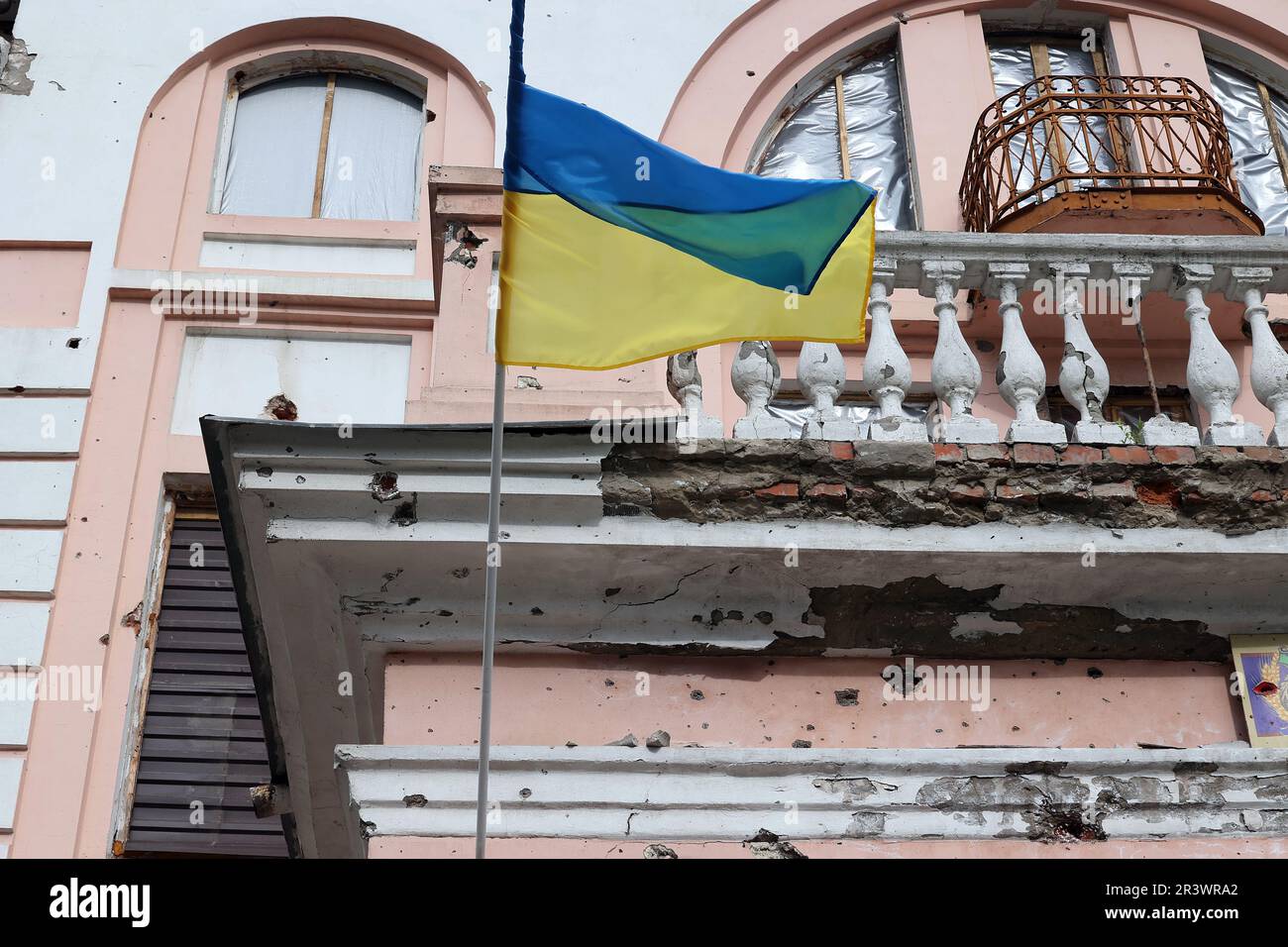 OKHTYRKA, UKRAINE - 24 MAI 2023 - Un drapeau ukrainien vole à l'extérieur d'un bâtiment du centre-ville endommagé par des bombardements russes, Okhtyrka, région de Sumy, non Banque D'Images