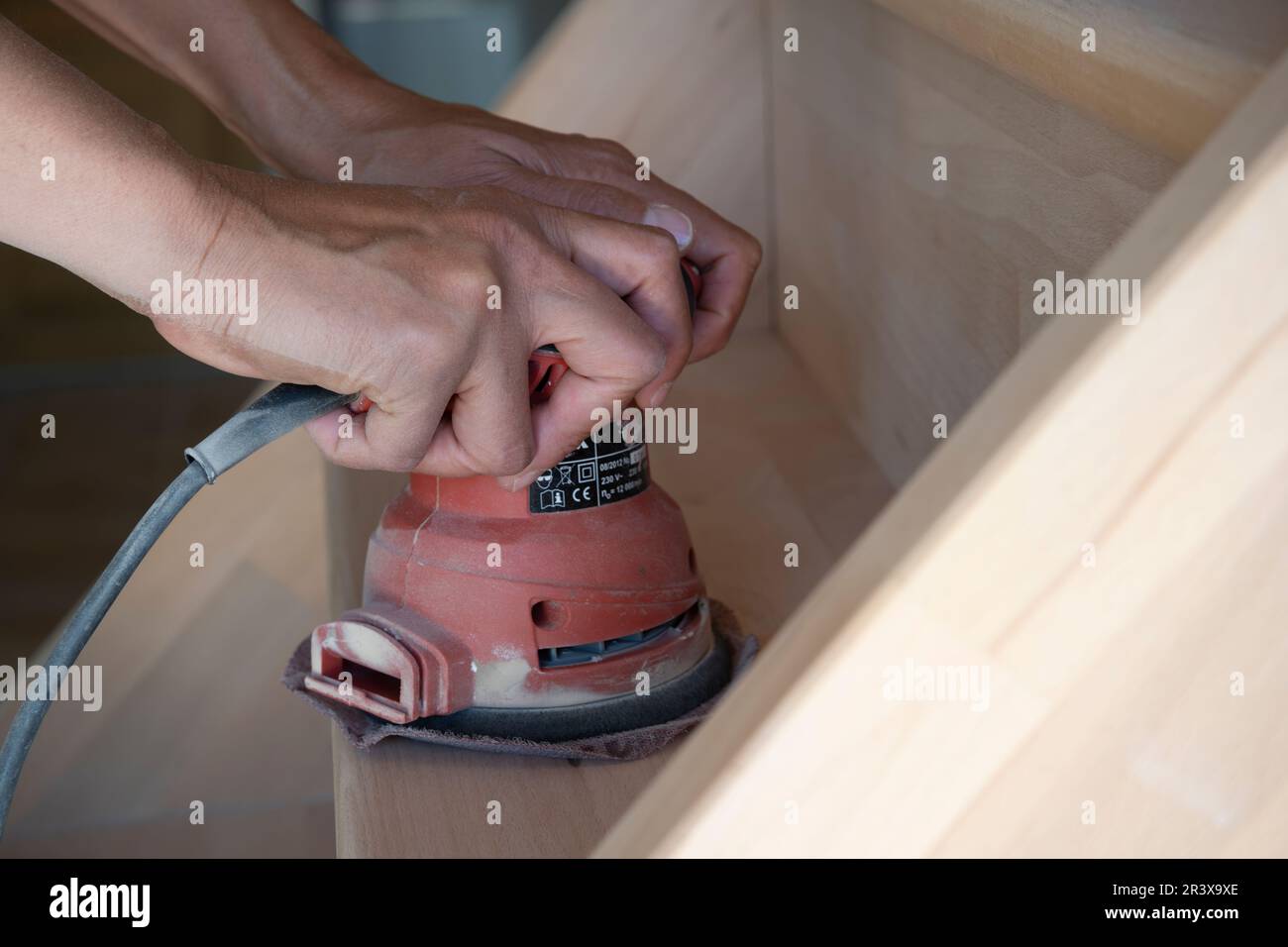 Gros plan d'une ponceuse manuelle contrôlée par une femme sablant des escaliers en bois, faites-le vous-même concept Banque D'Images