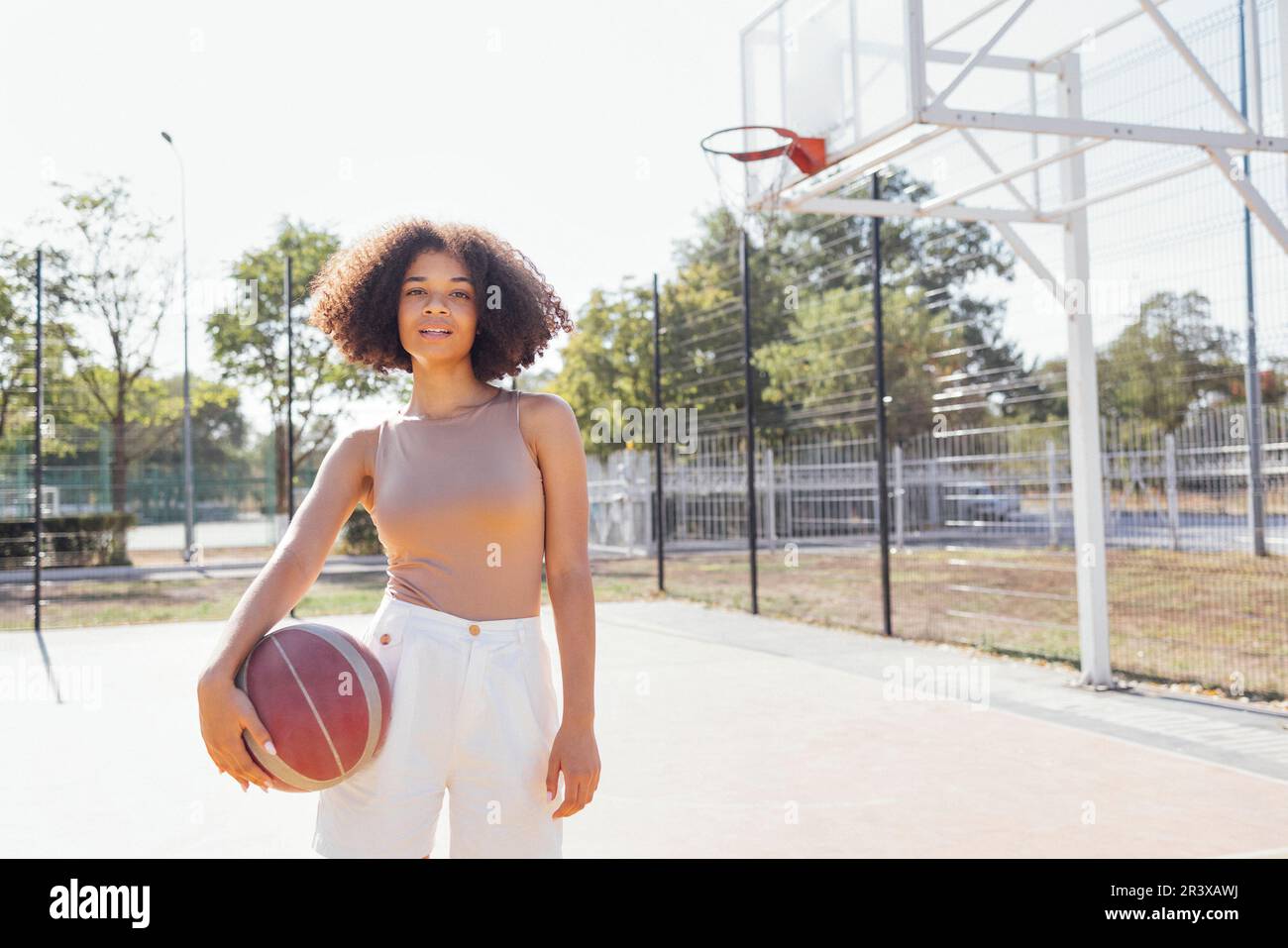 Une jeune fille élégante et fraîche se réunit sur le terrain de basket-ball, jouant au basket-ball à l'extérieur Banque D'Images