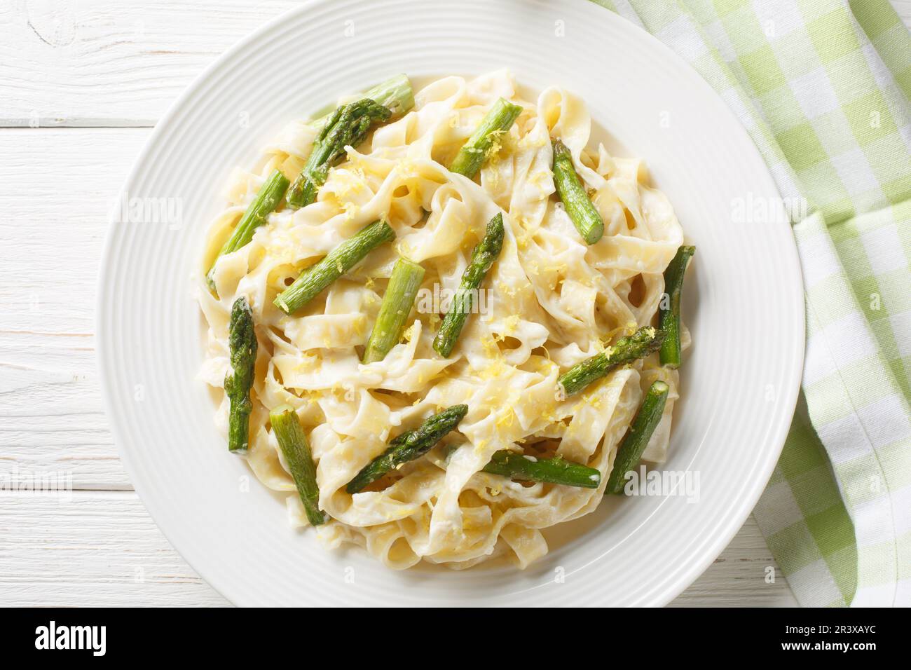 De délicieuses pâtes de fettuccine aux asperges, du citron à la sauce crémeuse au parmesan dans une assiette sur la table. Vue horizontale du dessus Banque D'Images