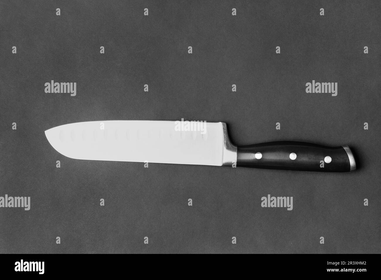 Couteau de cuisine avec poignée noire sur fond noir. Grand couteau sur fond sombre. Ustensiles de cuisine. Couteau à lame large. Banque D'Images