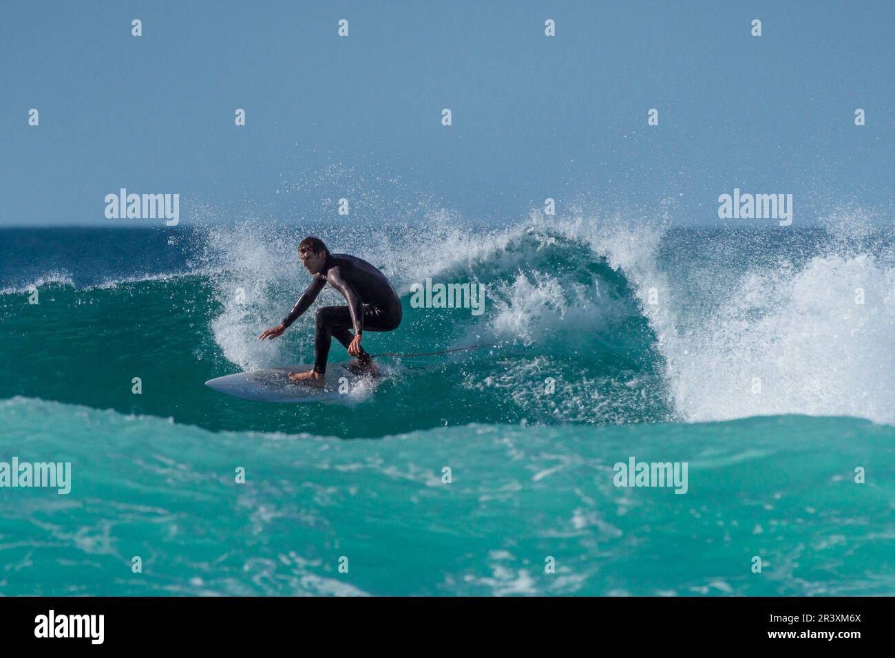 Une action de surf spétaculaire en tant que surfeur mâle fait une vague à Fistral à Newquay, en Cornouailles, en Angleterre, au Royaume-Uni. Banque D'Images