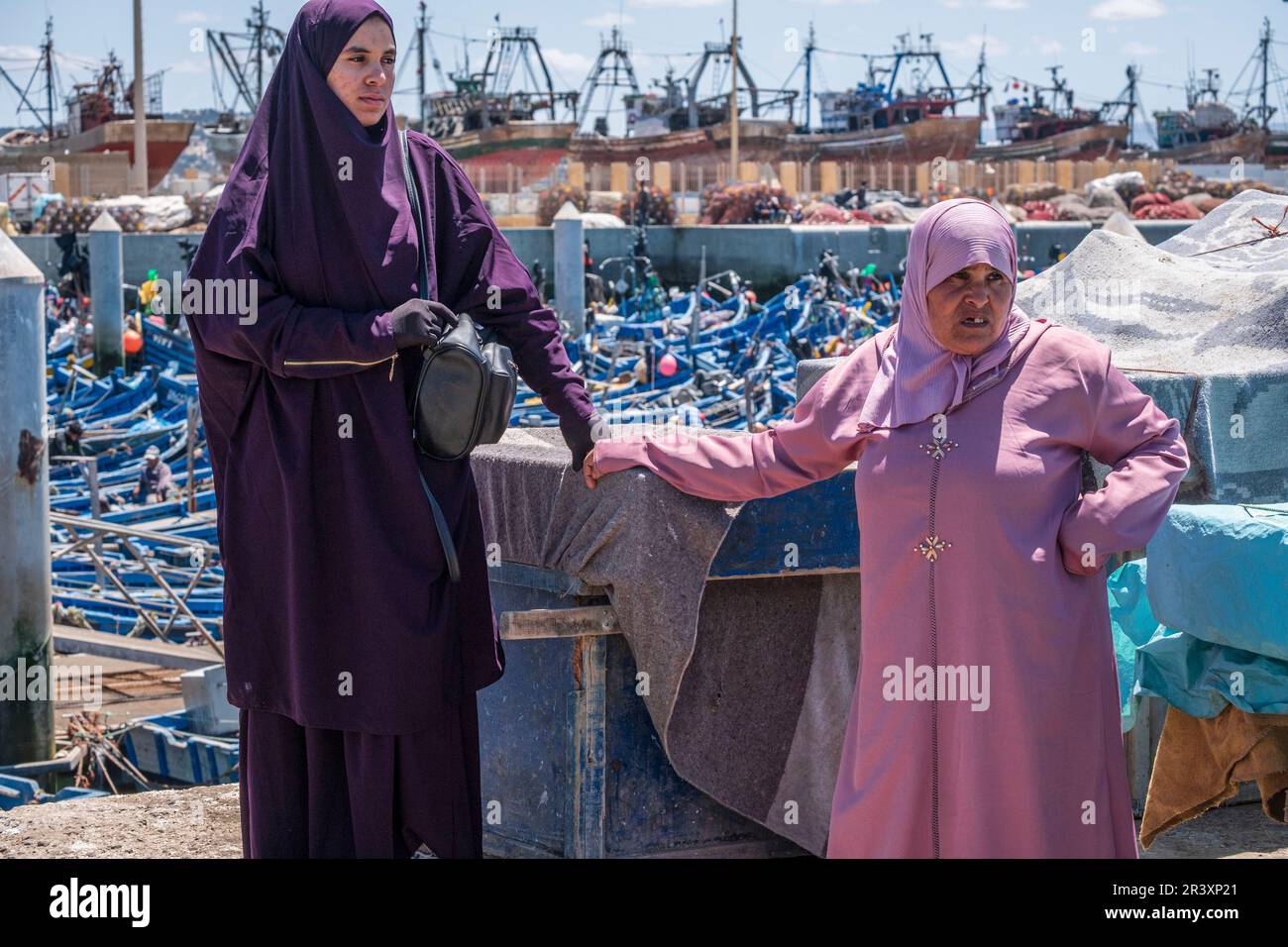 Deux femmes arabes attendant l'arrivée des bateaux de pêche, port de pêche, Essaouira, maroc, afrique. Banque D'Images