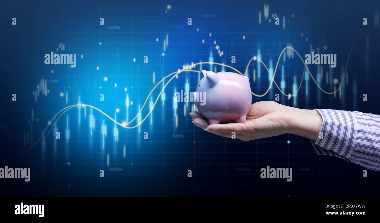 La main femelle tient une banque de piggy en céramique rose sur le fond d'un graphique holographique croissant. Concept de croissance du revenu, élevé m Banque D'Images