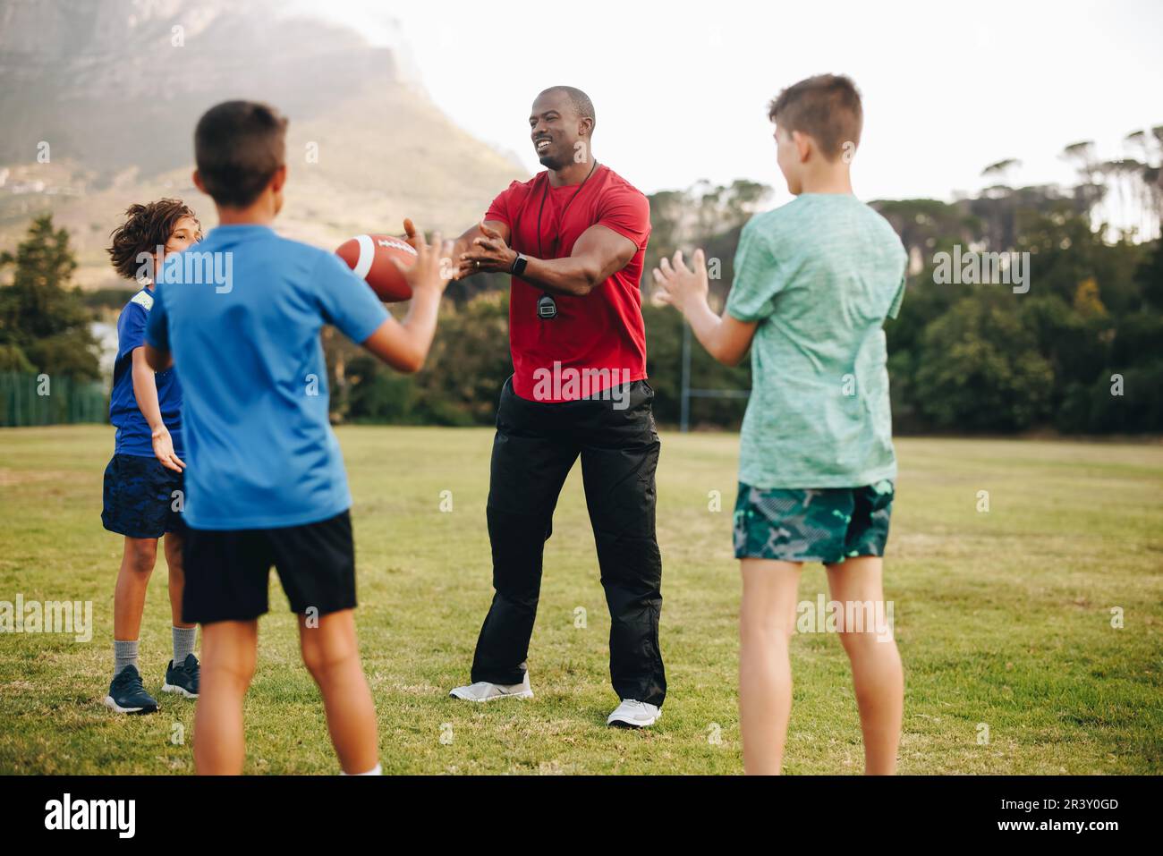 Session de rugby à l'école. Instructeur de sport entraîneur d'un groupe d'enfants dans un domaine. Pratique sportive et mentorat à l'école primaire. Banque D'Images