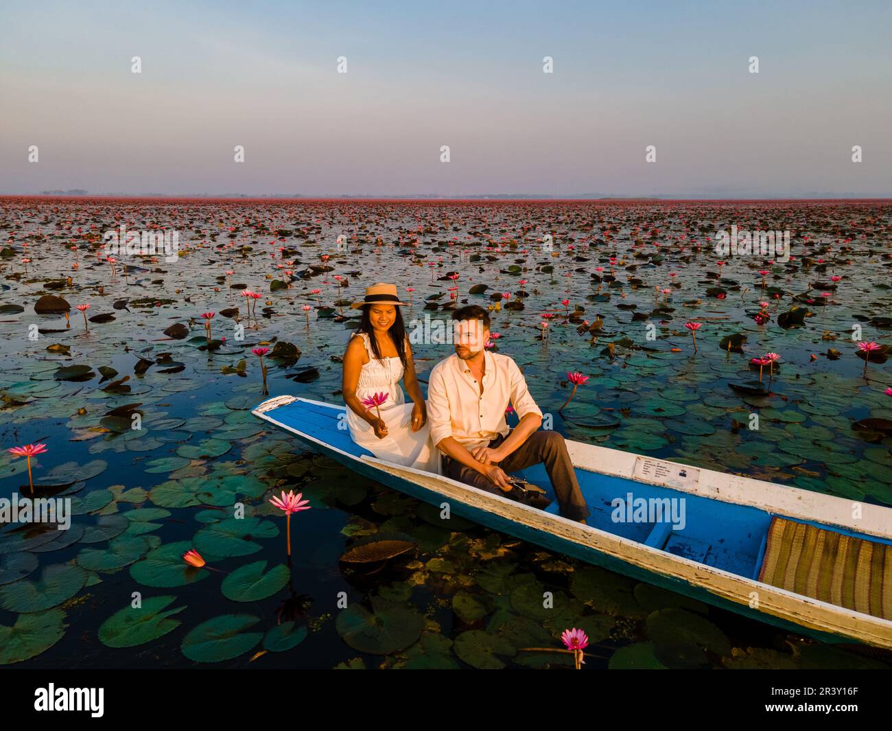 Couple dans un bateau à la mer de Lotus Rouge Kumphawapi plein de fleurs roses à Udon Thani en Thaïlande. Banque D'Images