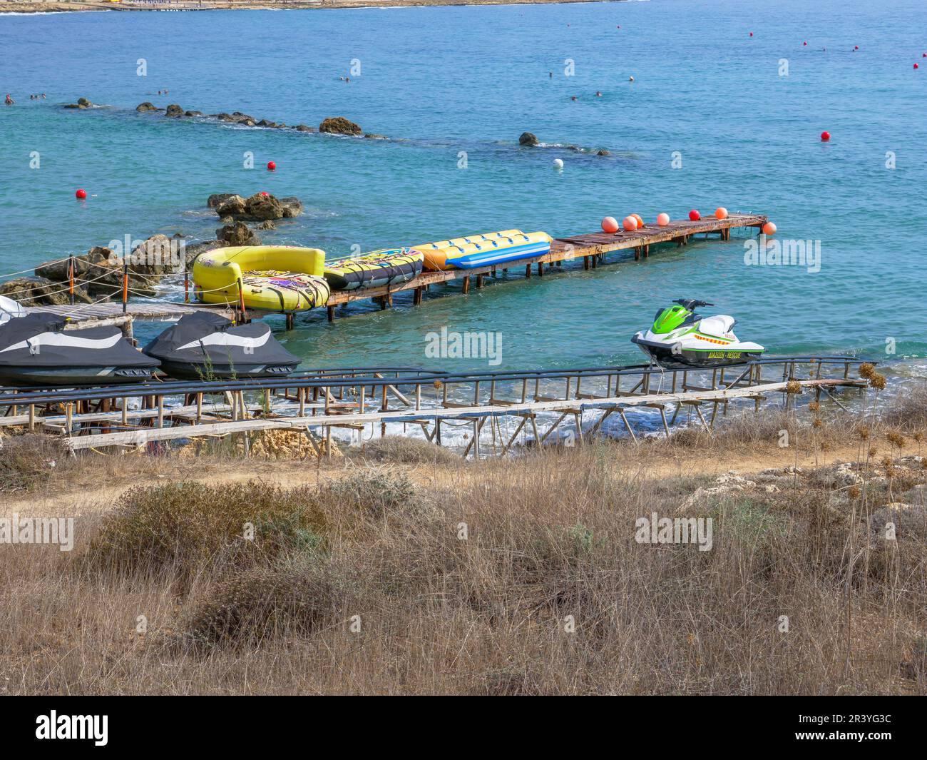 Scooter des mers, banana-boats gonflables, petits pains sur les rails descendant de la haute rive vers la mer Méditerranée à Ayia Napa. Banque D'Images