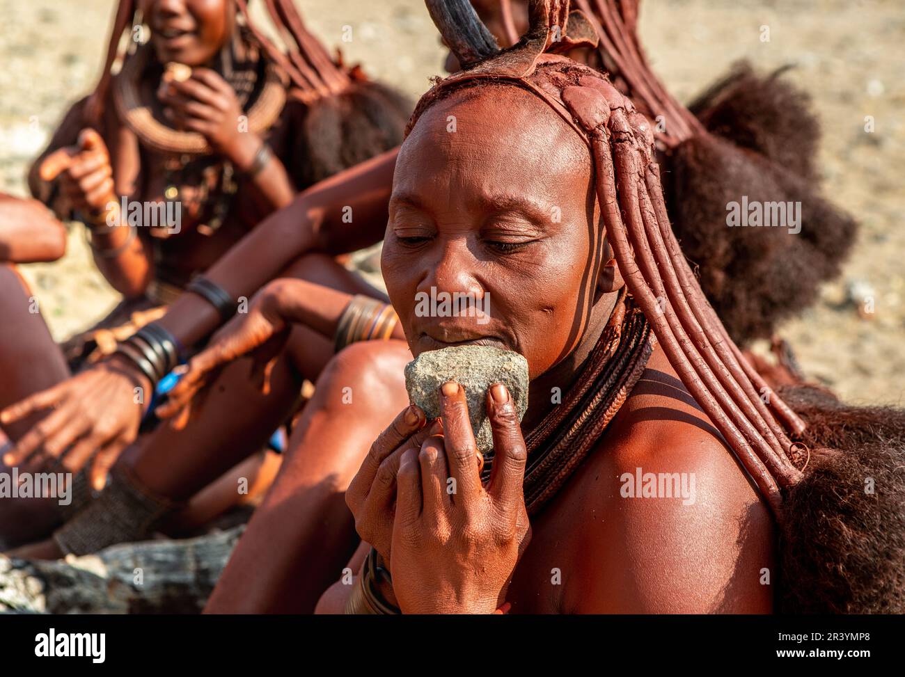 La femme Himba utilise la pierre comme serviette après avoir mangé. Banque D'Images