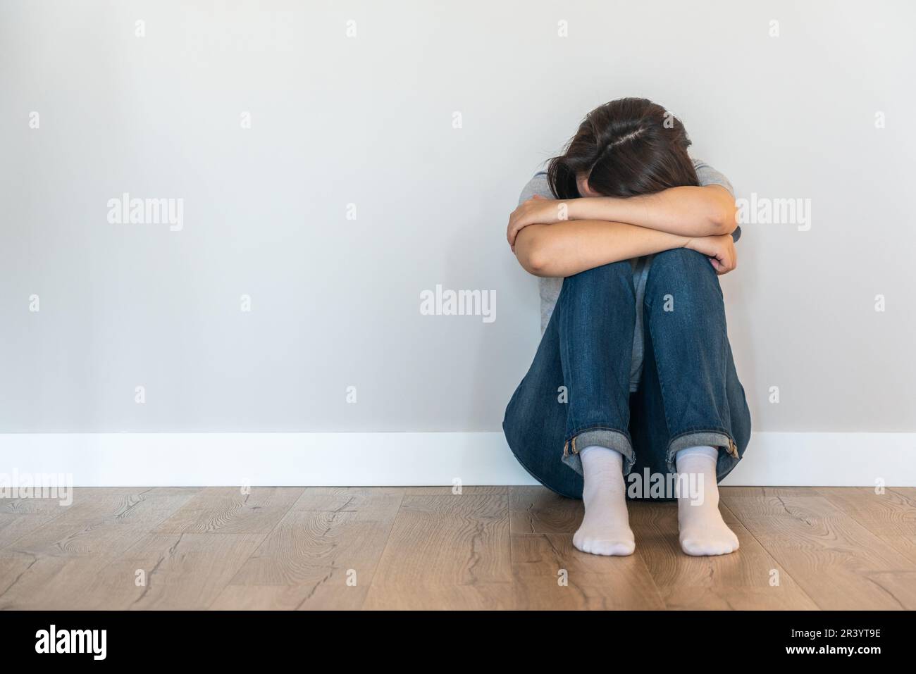 Triste femme assise sur un sol seul dans une pièce vide, désespoir et concept solitaire avec espace de copie Banque D'Images