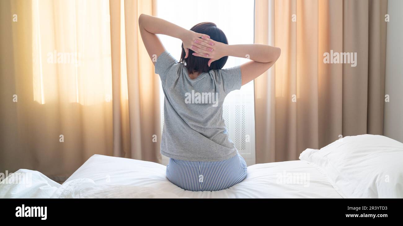 Pano de femme s'étirant dans le lit après le réveil, vue arrière Banque D'Images