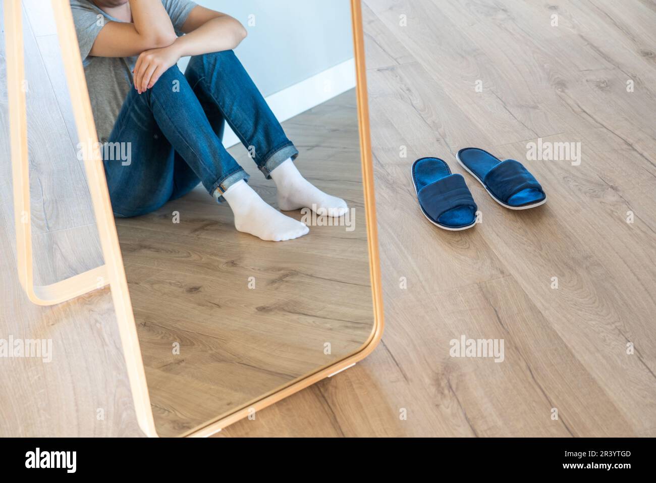 Réflexion dans le miroir d'une femme triste assise sur un sol seul dans la pièce vide, désespoir et concept solitaire avec espace de copie Banque D'Images