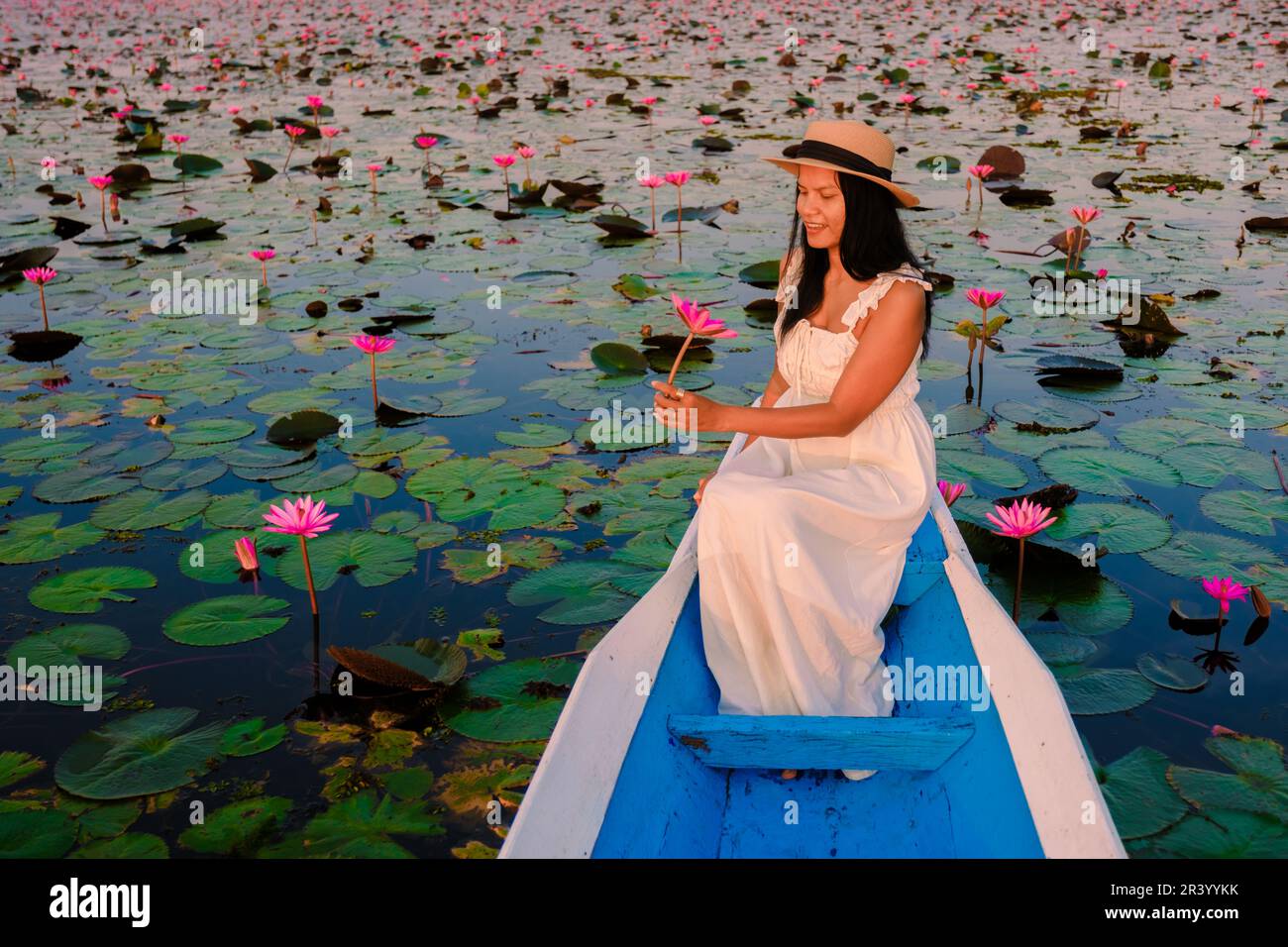 Femmes thaïes à la mer de Lotus rouge, lac Nong Harn, Udon Thani, Thaïlande, femme asiatique avec une robe et un chapeau dans un bateau en bois au lac de lotus rouge. Banque D'Images