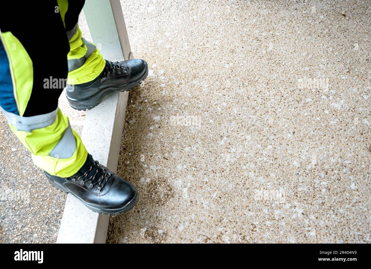 Jambes avec pantalon réfléchissant et bottes de travail noires Banque D'Images