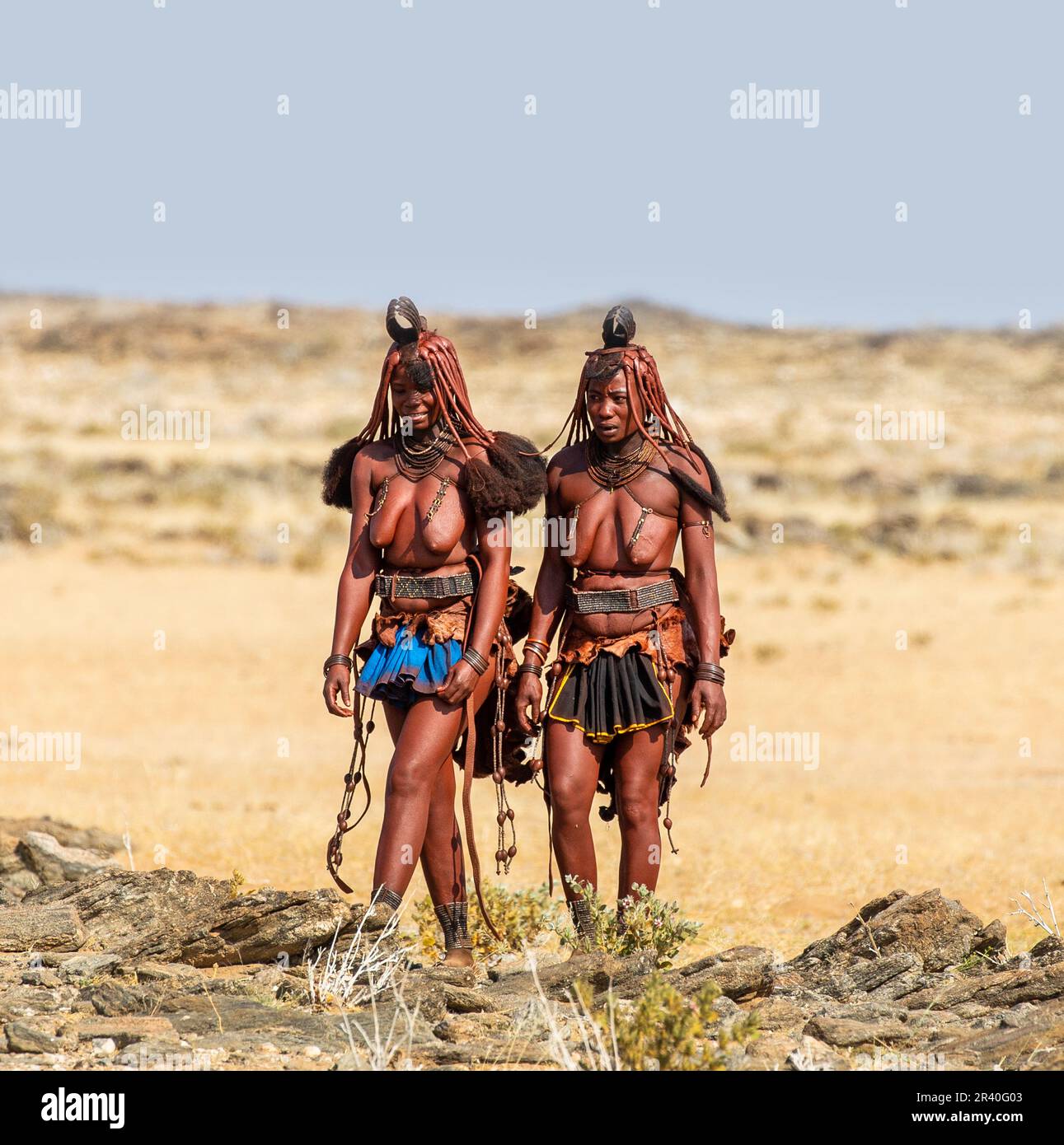 Deux femmes de la tribu Himba marchent dans le désert en vêtements nationaux. Banque D'Images