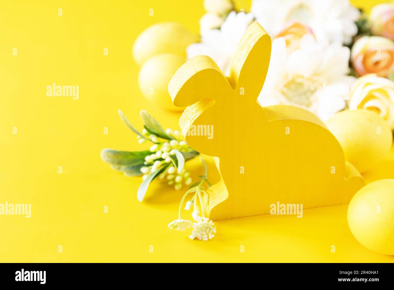 Composition de Pâques avec œufs colorés, lapin en bois et fleurs de printemps sur fond jaune. Copier l'espace. Banque D'Images
