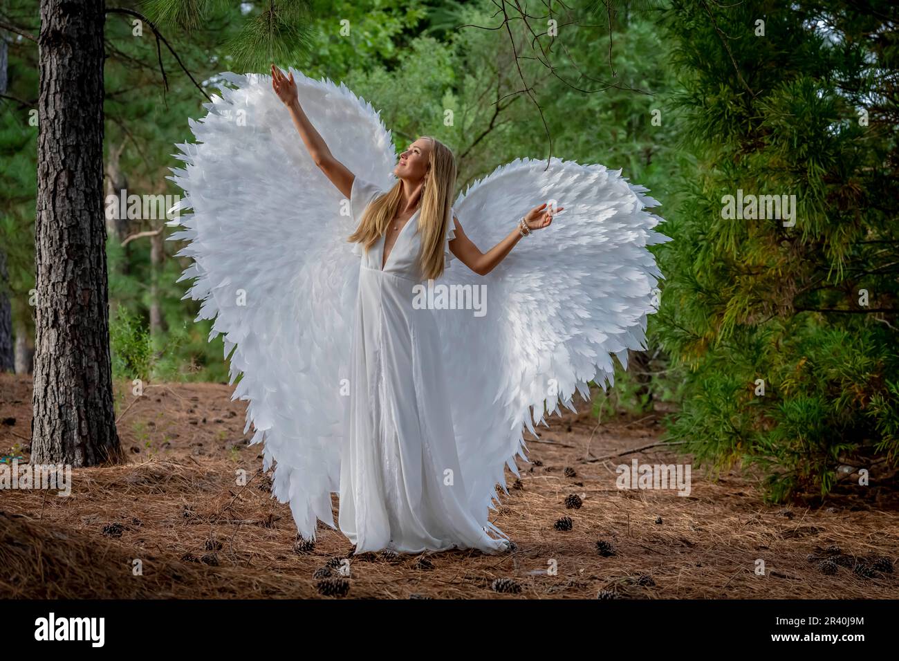 Un joli modèle Blonde pose à l'extérieur tout en portant des ailes blanches faites à la main pour Halloween Banque D'Images