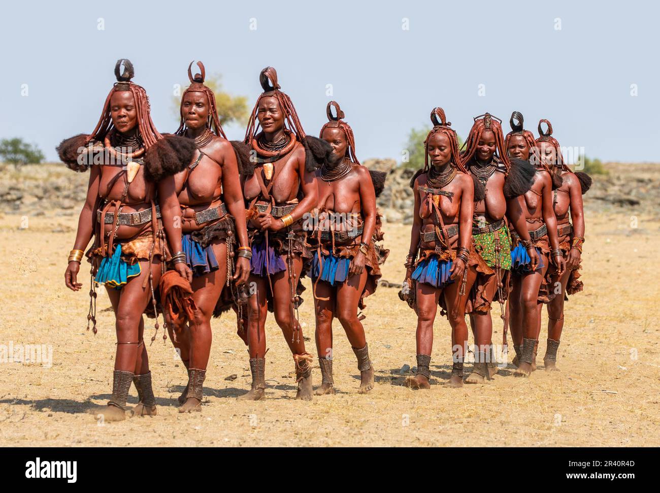 Groupe de femmes de la tribu Himba marche dans le désert en vêtements nationaux. Banque D'Images