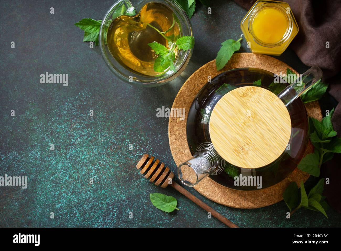 Thé vert à base de plantes thérapeutiques. Thé chaud avec des minthes de miel dans une théière en verre sur une table en pierre. Plan d'agencement avec vue de dessus. Copier l'espace. Banque D'Images