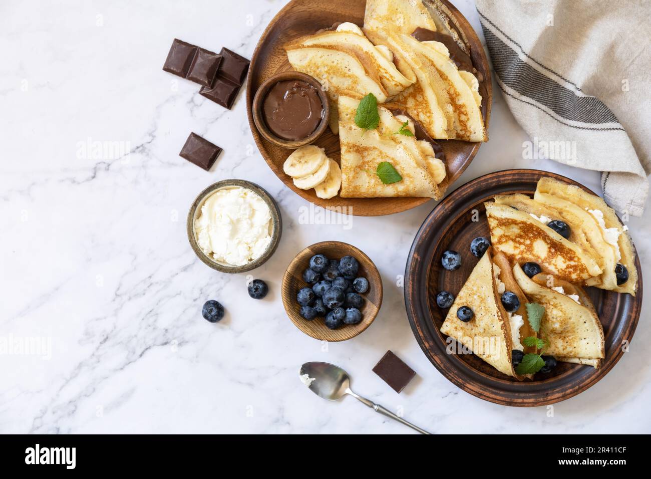 Fête du Pancake, petit déjeuner sain. Délicieuses crêpes maison au caramel au chocolat, aux bananes, aux bleuets et au ricott Banque D'Images