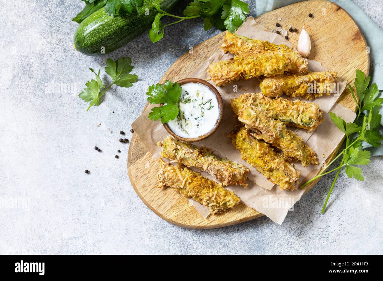 En-cas savoureux et sains, repas d'été. Frites courgettes. Bâtonnets de courgettes croustillants dans de la chapelure, avec du fromage et de la sause à l'ail. V Banque D'Images
