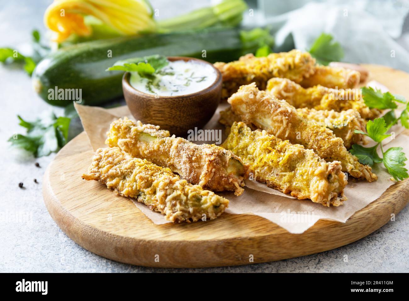 En-cas savoureux et sains, repas d'été. Frites courgettes. Bâtonnets de courgettes croustillants dans de la chapelure, avec du fromage et de la sause à l'ail. Banque D'Images