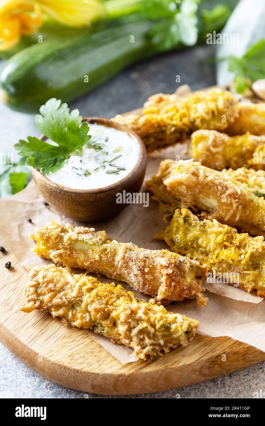 En-cas savoureux et sains, repas d'été. Frites courgettes. Bâtonnets de courgettes croustillants dans de la chapelure, avec du fromage et de la sause à l'ail. Banque D'Images